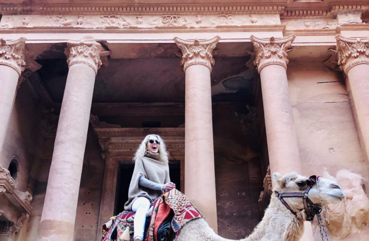 Riding a camel in front of a columned building
