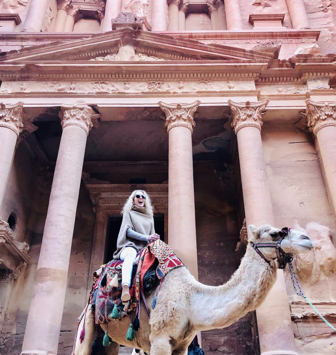 Riding a camel in front of a columned building
